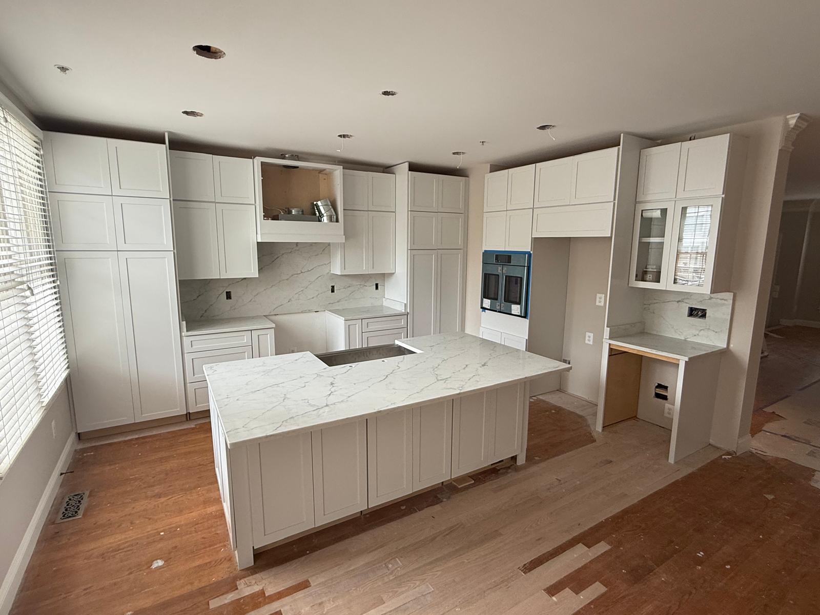 Custom white shaker kitchen cabinets installation with marble island